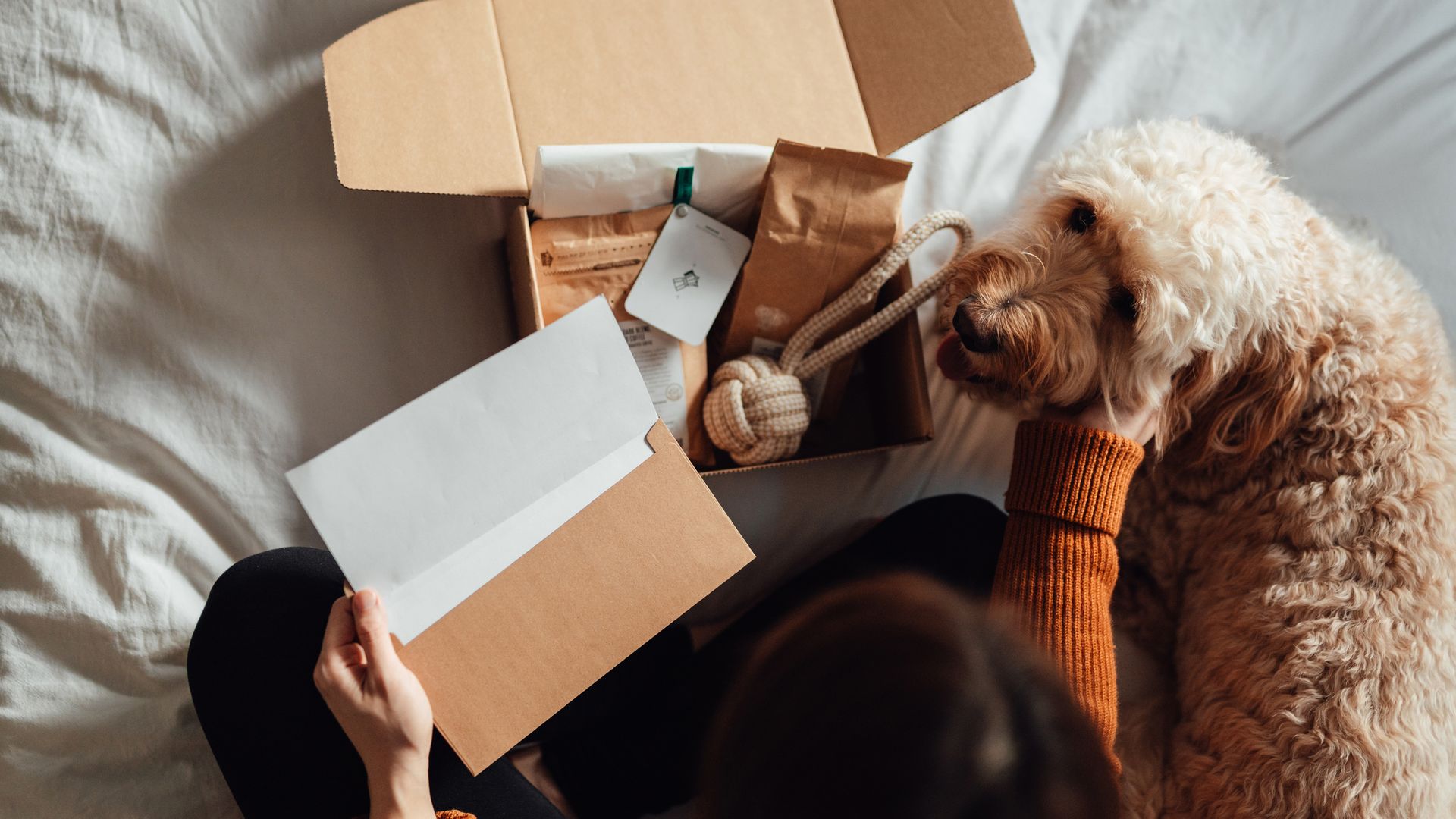 Una chica con un perro y varios regalos en una caja