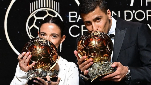 Plano medio de Aitana Bonmatí y Rodri Hernández besando sus balones de Oro