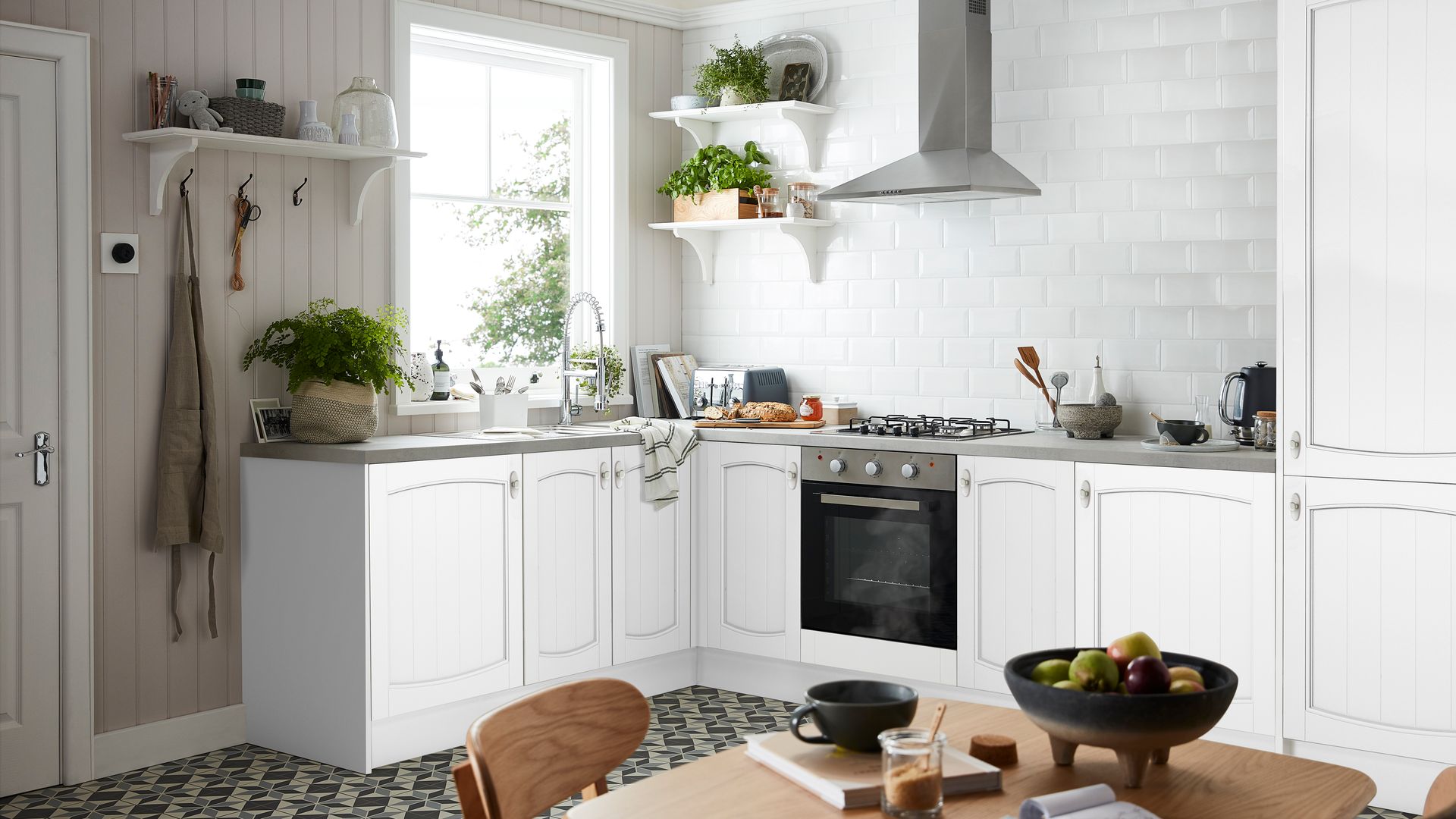 Cocina abierta, de estilo clásico con azulejos y muebles blancos, mesa de comedor de madera, baldas