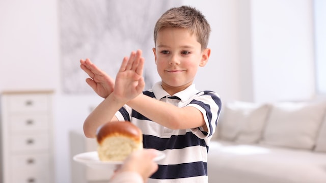 Niño rechazando una pieza de bollería en su casa