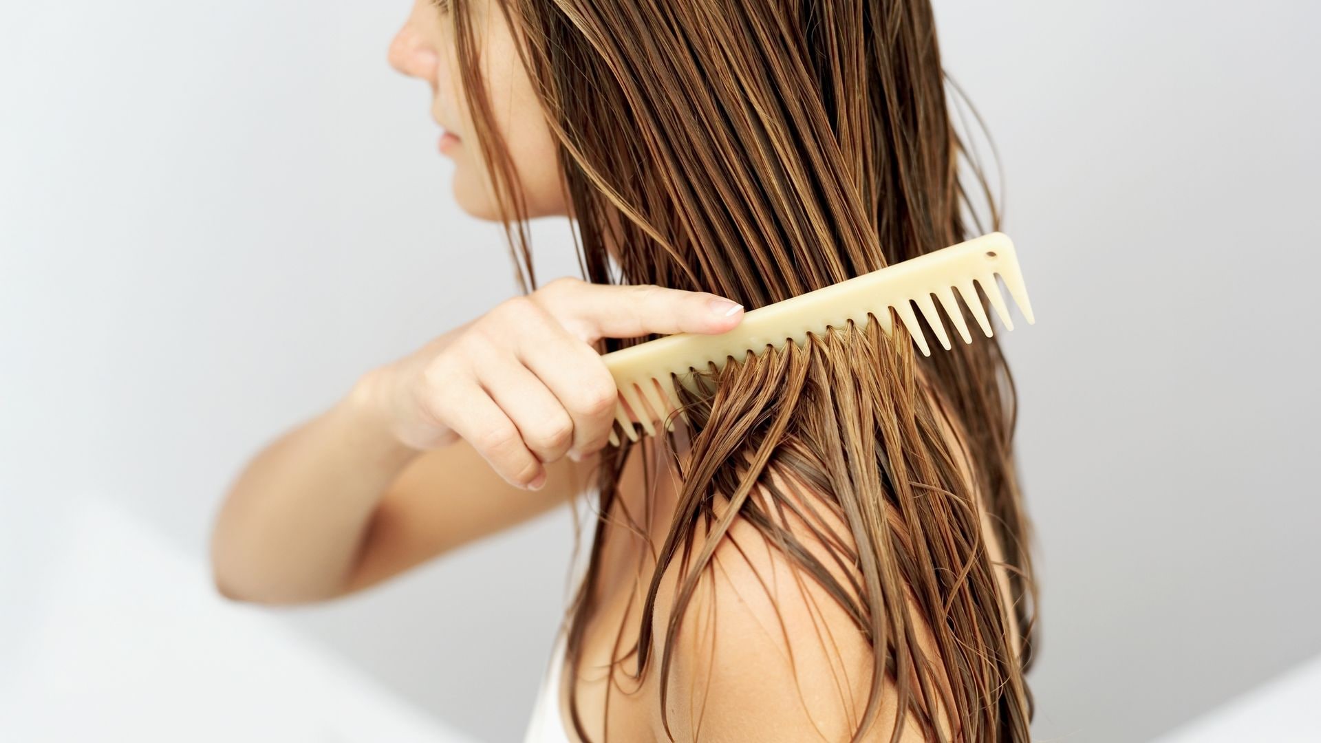 Mujer peinándose cabello húmedo