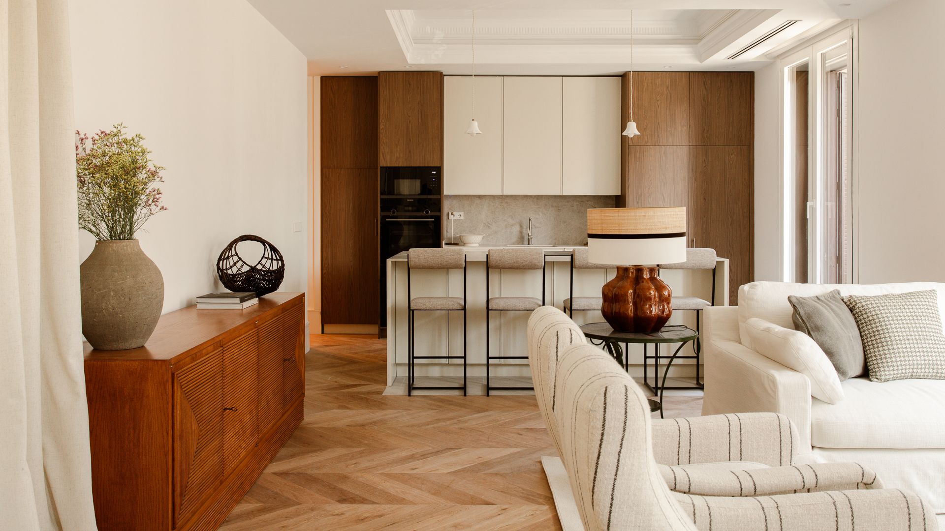 Cocina abierta al salón con muebles de madera y blancos, isla de cocina, aparador 