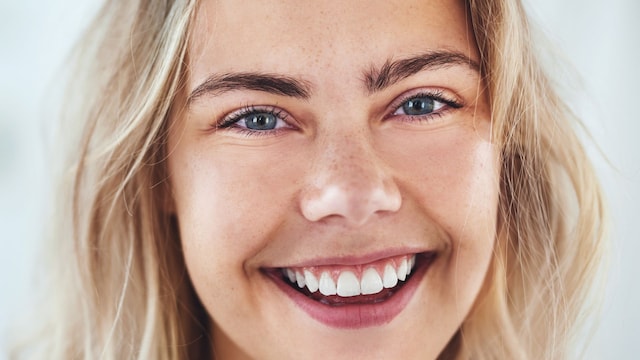 Chica joven rubia de ojos azules sonriendo a la cama en primer plano