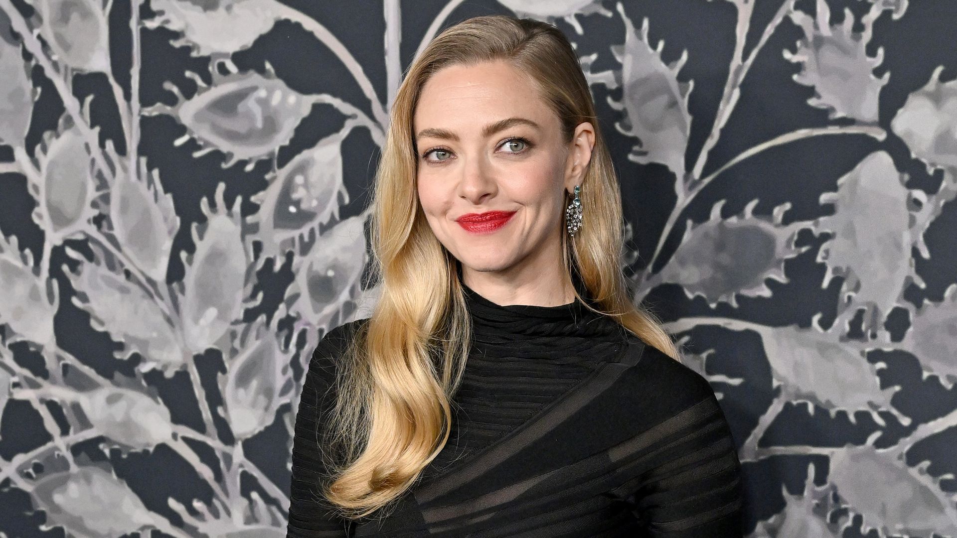Amanda Seyfried con vestido negro, labios rojos y melena ondulada en el estreno de El testamento de Ann Lee