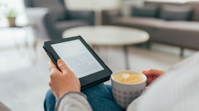 Una mujer con un café usando un eReader