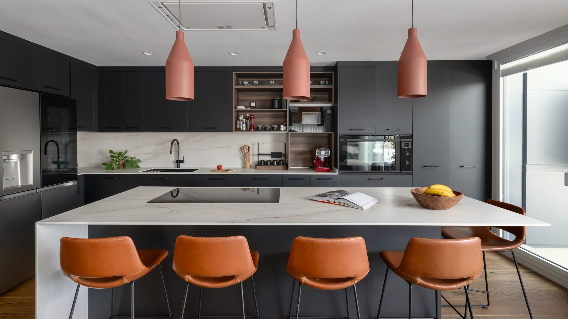 Cocina con isla, muebles negros, encimera blanca, taburetes altos de cuero, lámparas de techo 