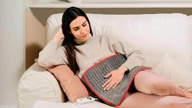 Una chica con una esterilla eléctrica sobre el abdomen 