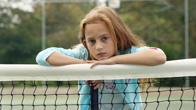 Niña seria en una cancha de tenis