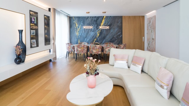 Salón comedor con sofá blanco, cojines rosas, mural en la pared del comedor, puerta corredera de madera 