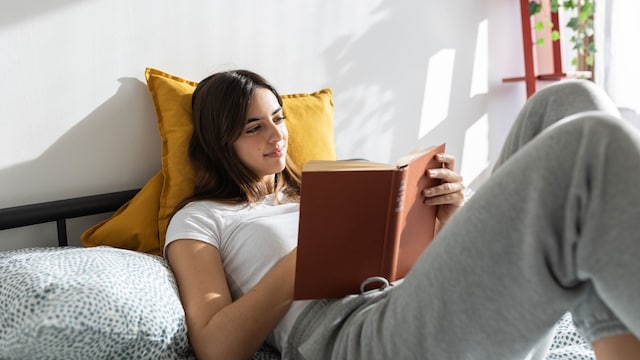 Mujer leyendo un libro de amor en la cama