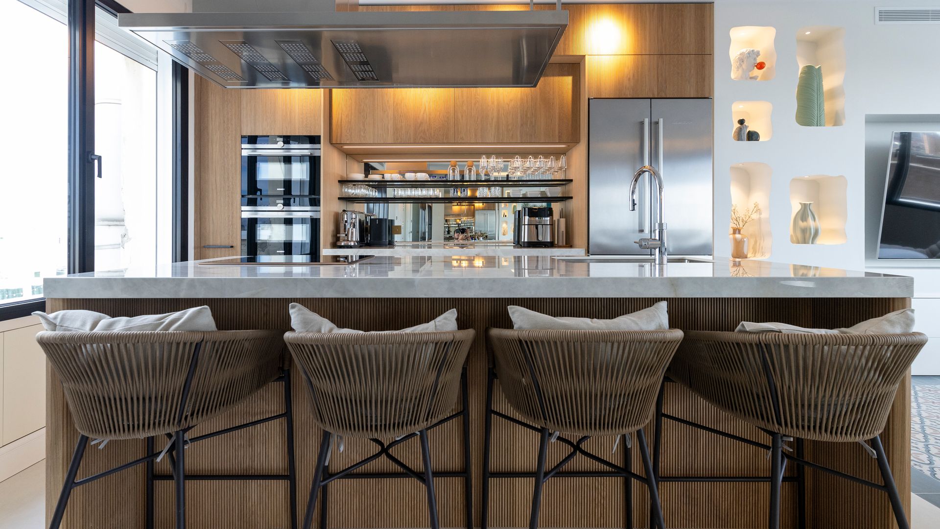 Cocina con isla de madera, taburetes de fibras, encimera de acero