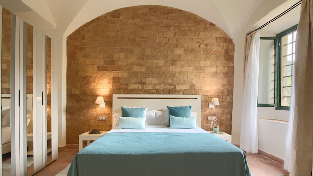 Dormitorio con pared de piedra y ropa de cama azul