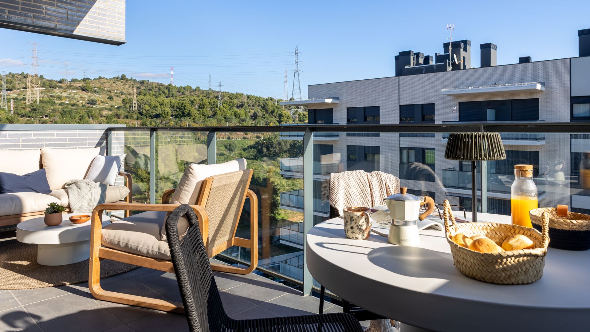 Terraza pequeña, a modo balcón, con zona de estar y zona de comedor con mesa redonda 
