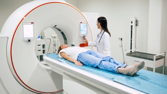 Médico radiólogo profesional en laboratorio médico controla la resonancia magnética o la tomografía computarizada o la exploración PET con una paciente femenina sometida al procedimiento.