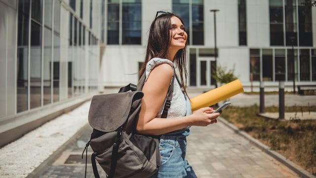 Mujer joven en la universidad con vaqueros, top de tirantes y mochila