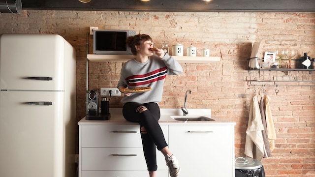 mujer comiendo pizza en la cocina