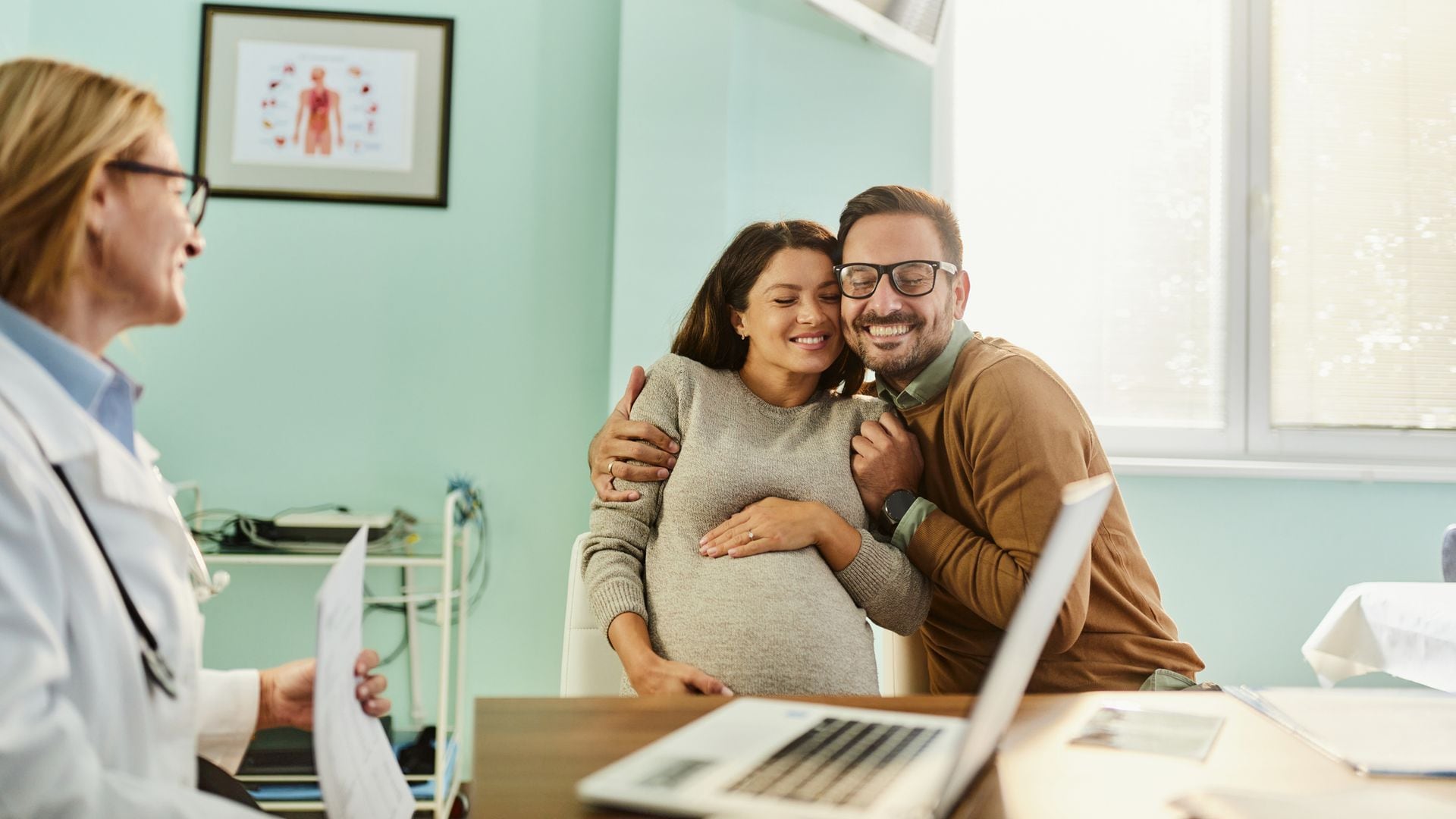 Embarazada, feliz junto a su pareja en la consulta de la ginecóloga