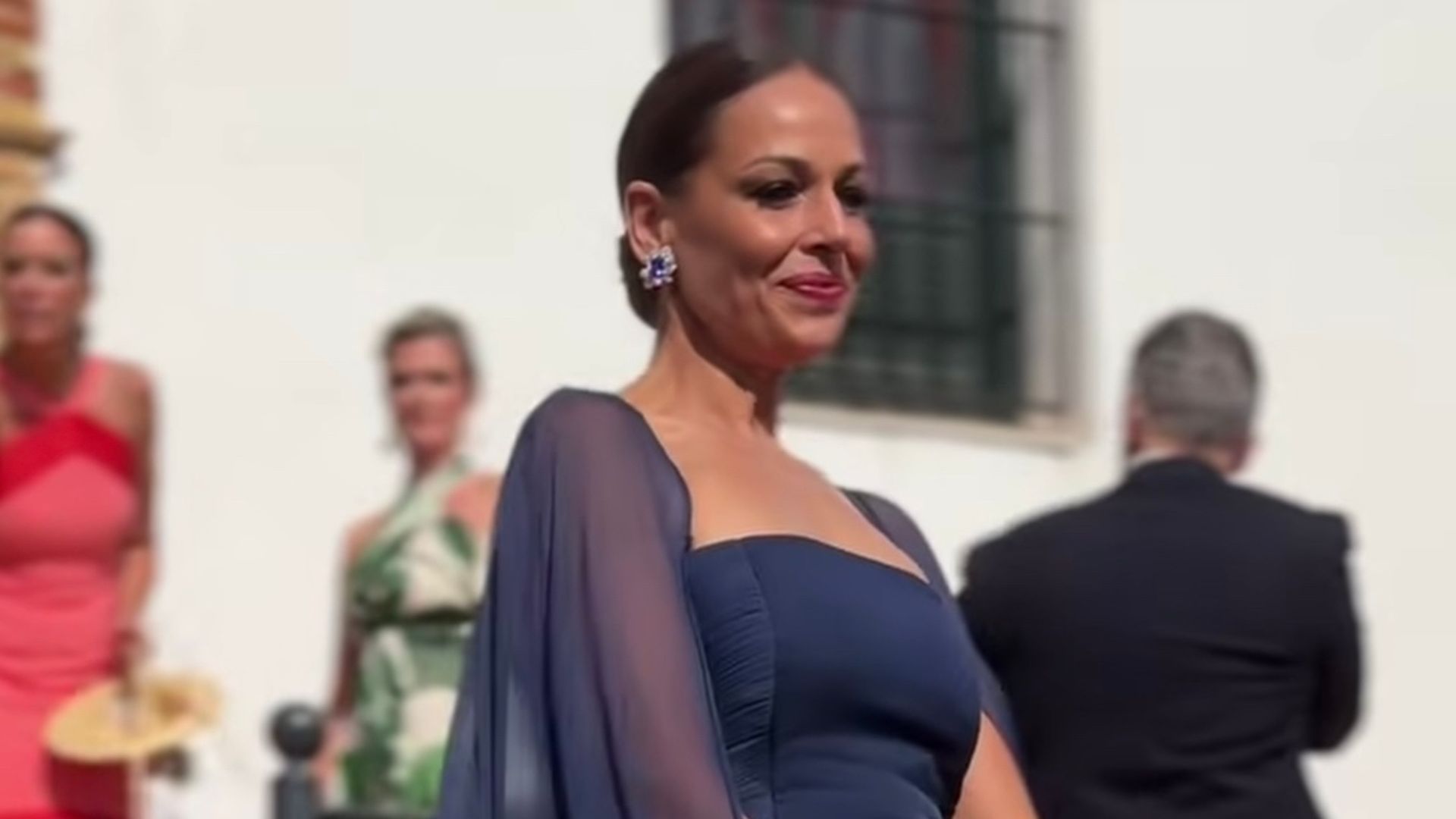 Eva González vuelve a la iglesia donde se casó para la boda de su prima con un espectacular vestido azul con escote italiano y capa de seda.