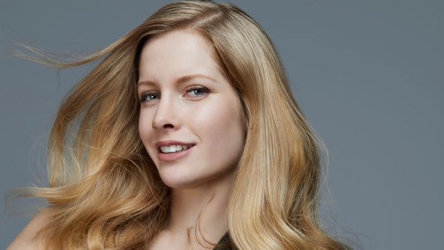 Rostro de mujer sonriente con cabello rubio ondulado y voluminoso
