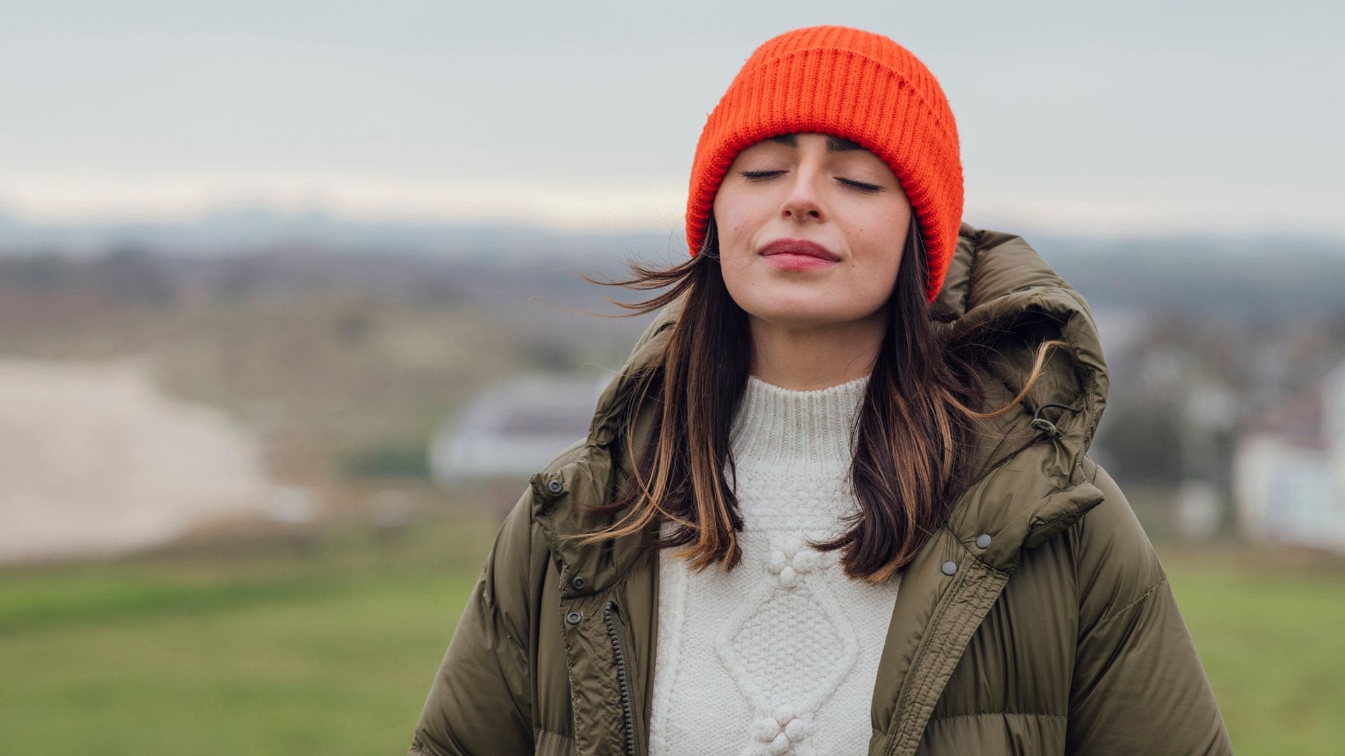 Mujer con gorro rojo en el campo respirando