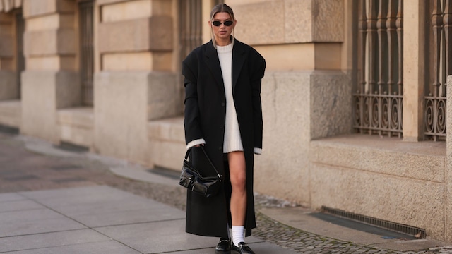 Sophia Geiss con vestido de punto blanco y abrigo negro en Berlin