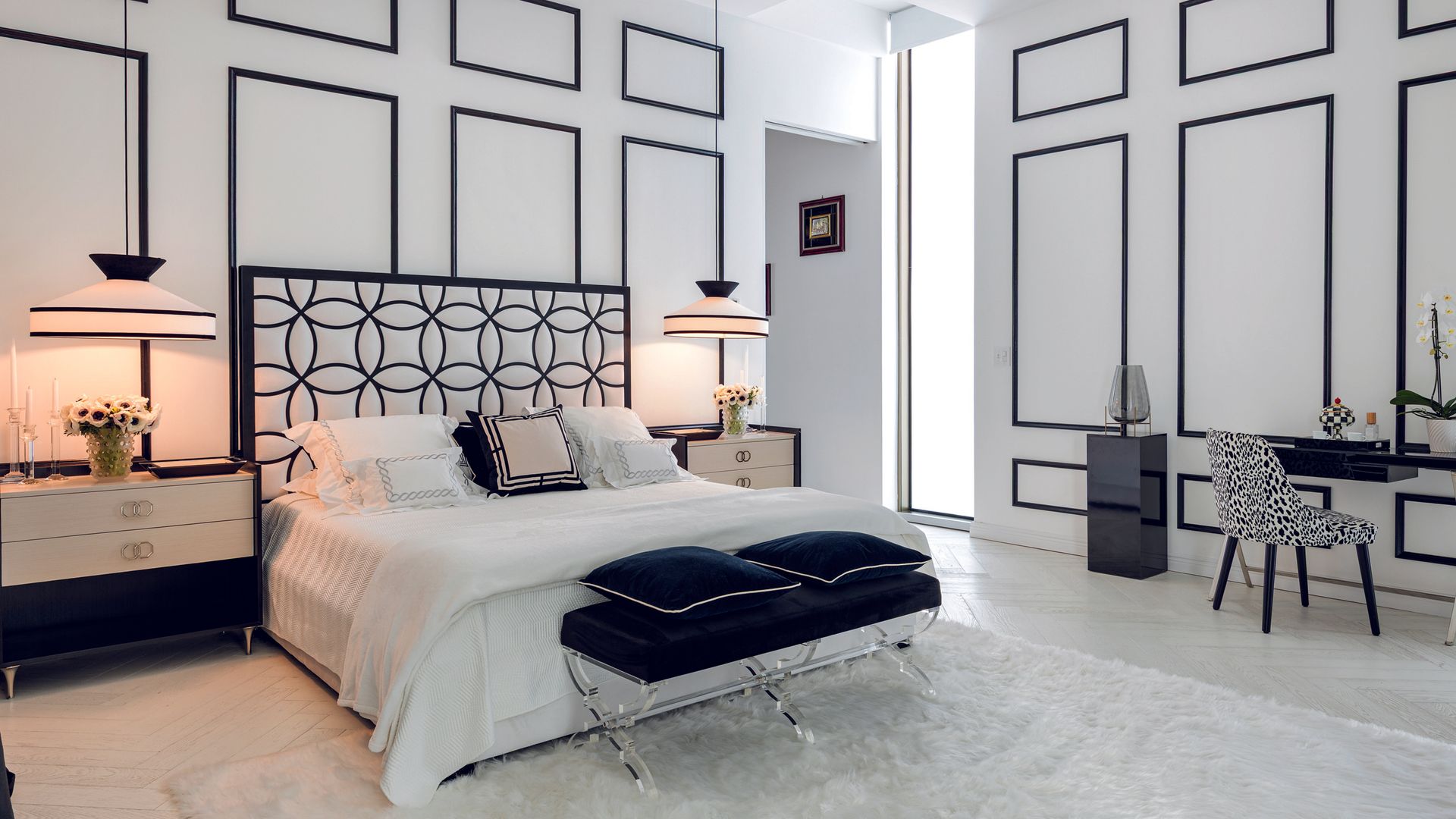 Habitación blanca con cama grande, almohadas azules, y mobiliario elegante. No se detectan celebridades.