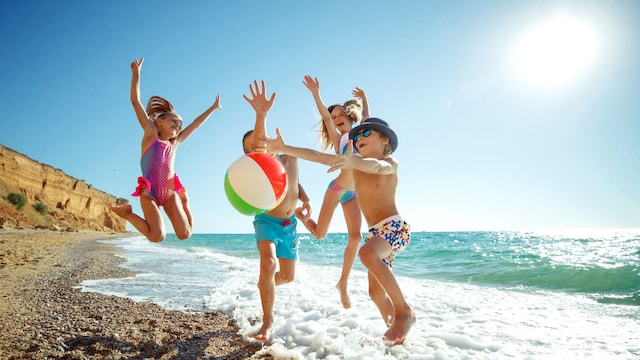 Niños divirtiéndose en la playa de arena en verano.