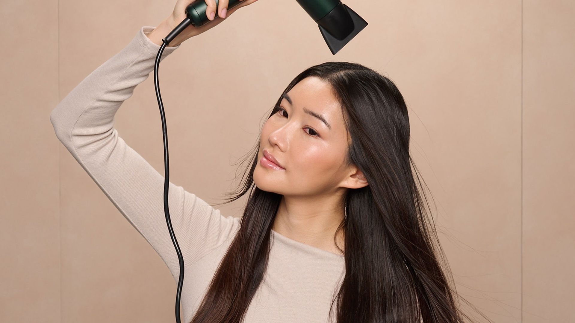 Mujer asiática con pelo largo moreno secándose la melena con un secador de BaByliss