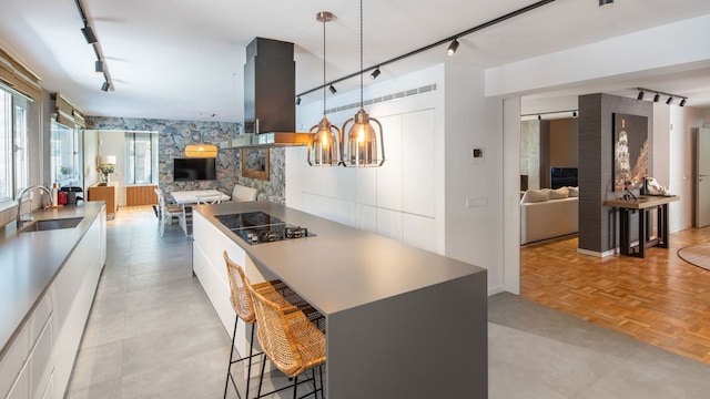 Espacio abierto con recibidor, cocina con isla, office, suelo de madera, lámparas de techo