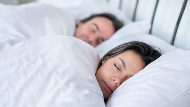 Una pareja durmiendo en la cama cubiertos por un edredón nórdico