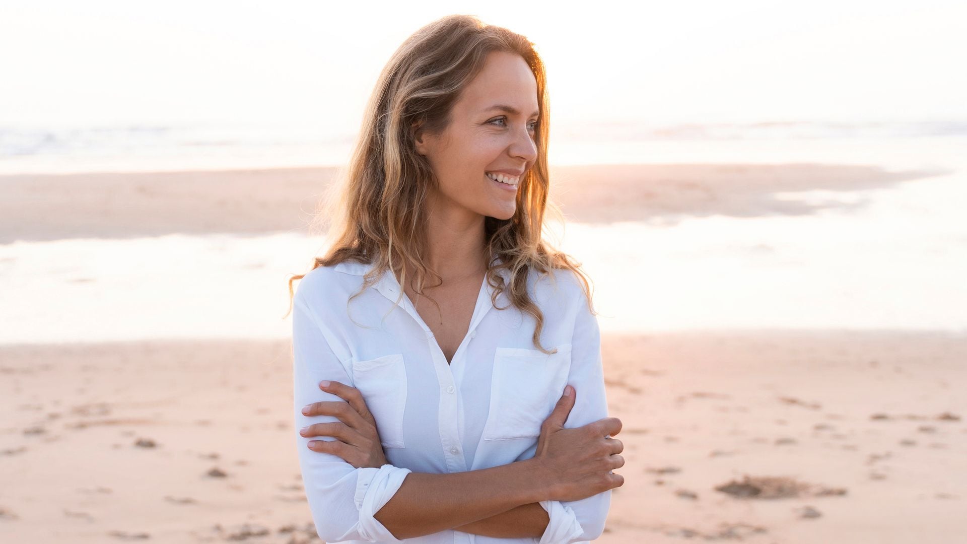 mujer sonriente sobre la arena de la playa