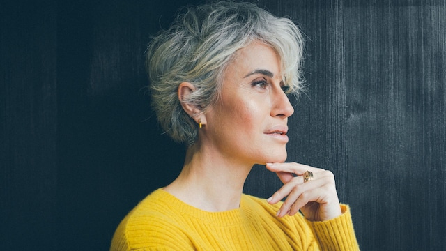 Mujer con pelo blanco mirando pensativa hacia el horizonte en primer plano