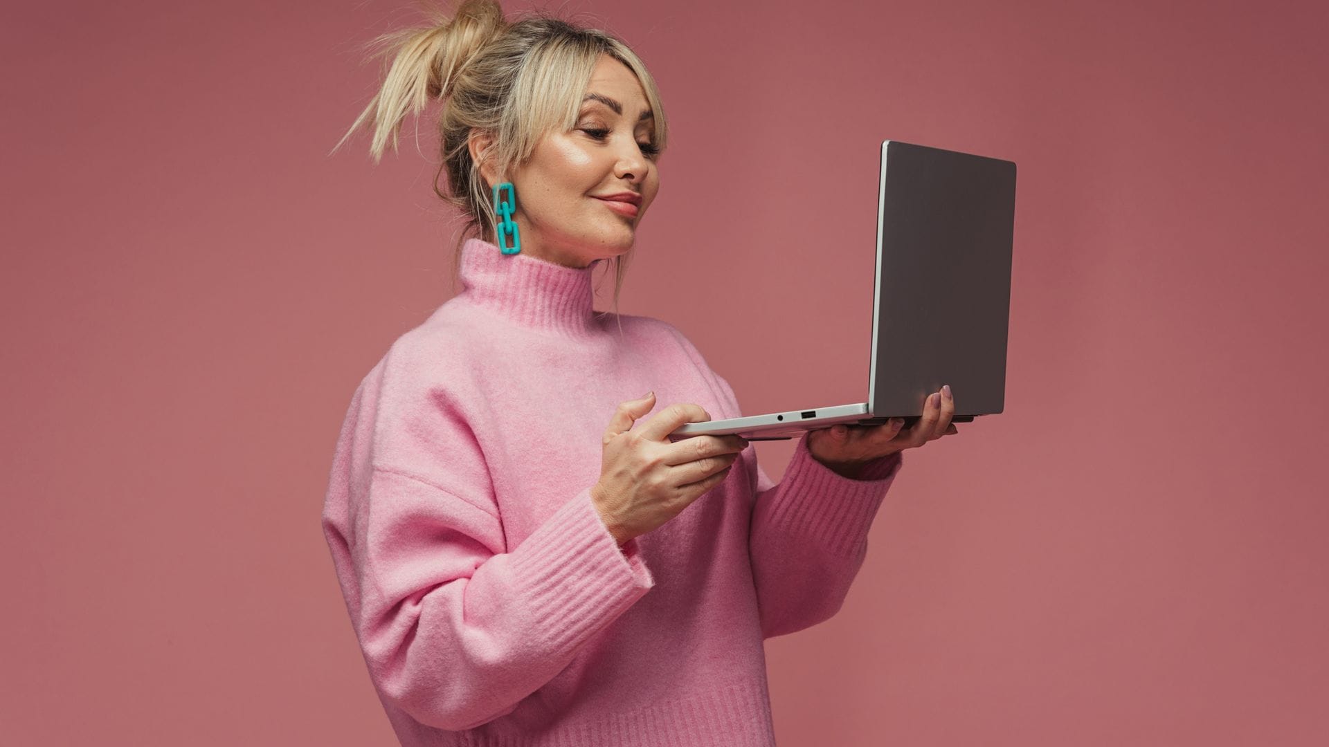 Una chica con un portátil y un jersey rosa