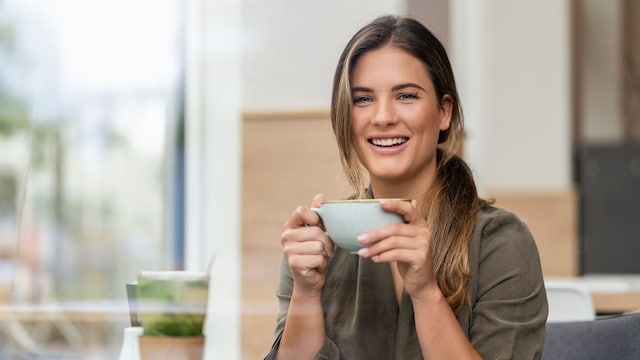 Mujer sonriendo en una terraza con una taza de té o café en una terraza
