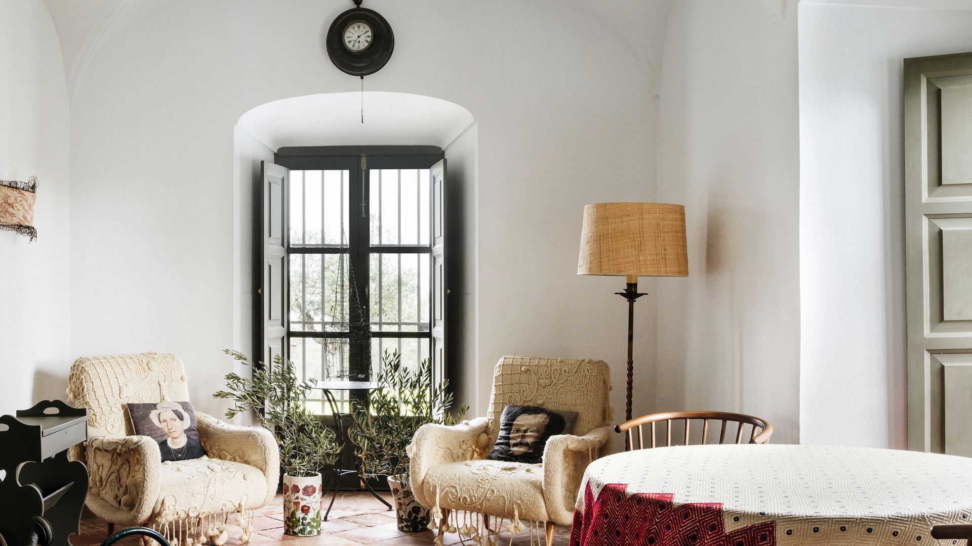 Sala con sillas, mesa cubierta, lámpara, y reloj