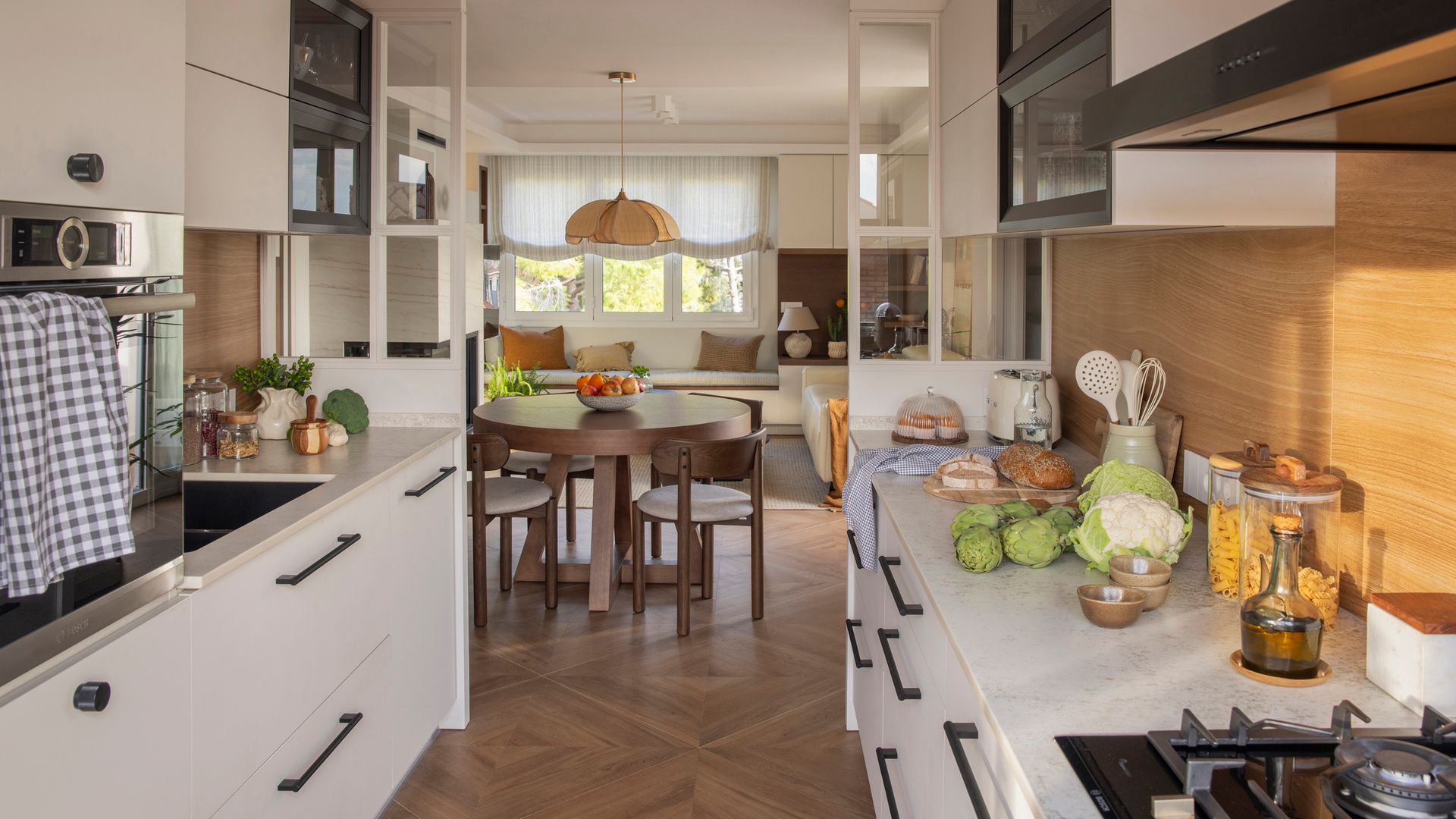 Cocina semiabierta con salida al comedor y al salón, muebles blancos, paneles fijos blancos con cuarterones de cristal 