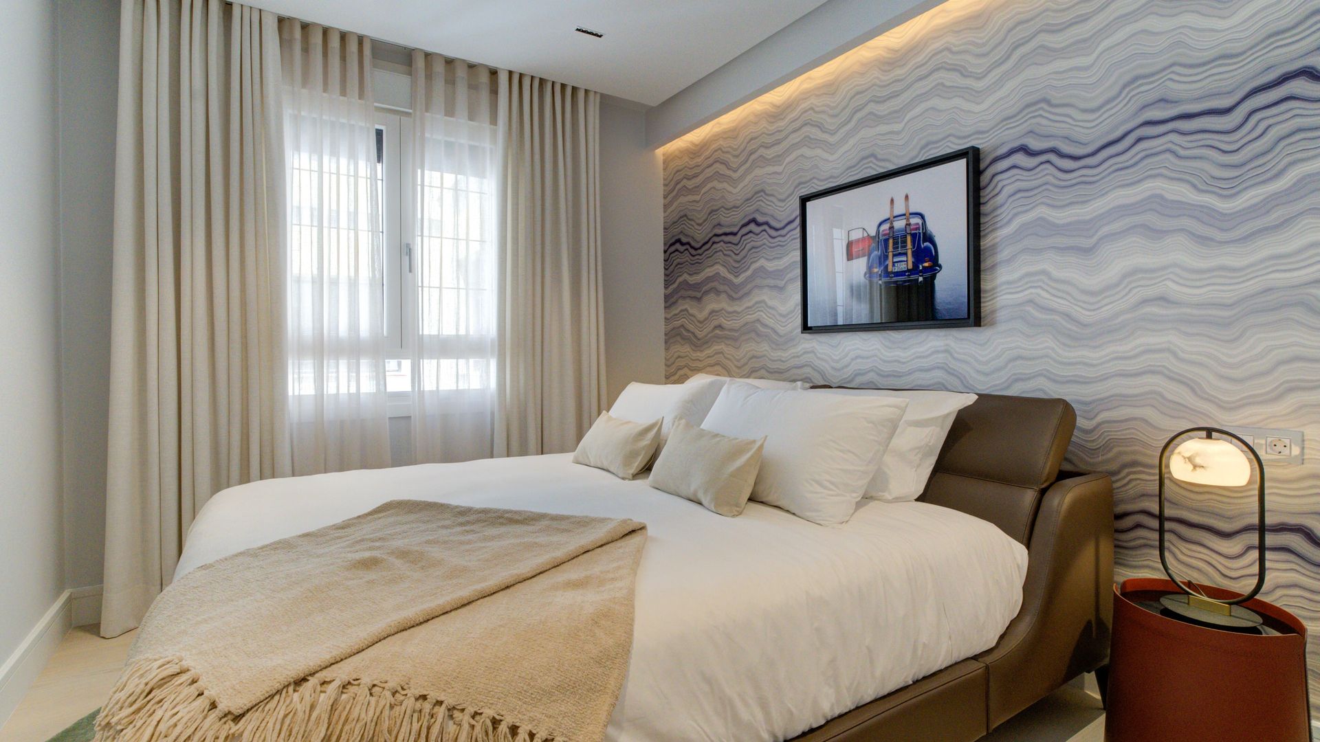 Dormitorio con falso techo, cortinas, pared del cabecero con papel pintado, cama de cuero