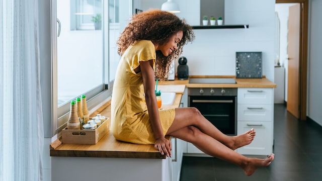 Mujer en la cocina con las sentada en la encimera con las piernas ligeras
