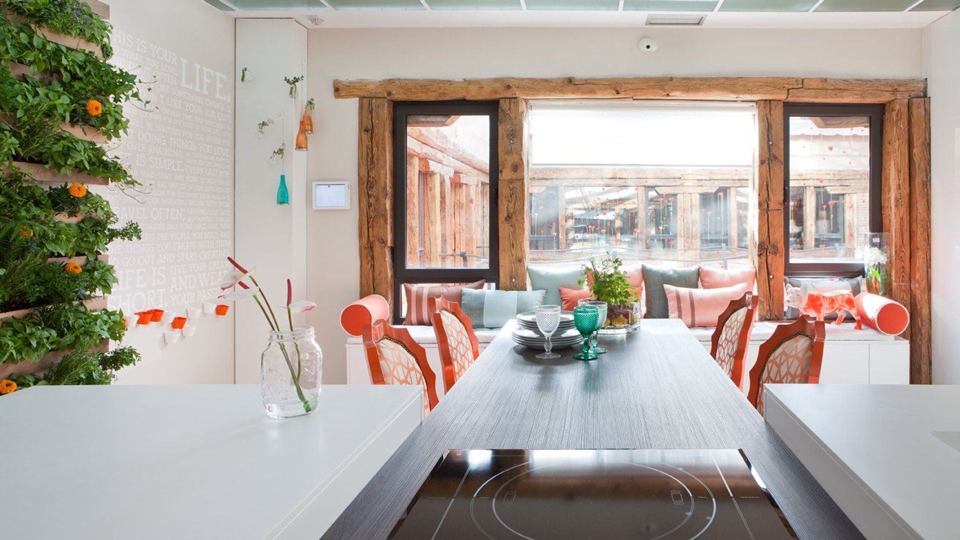 Cocina con comedor, placa de vitrocerámica, sillas naranjas antiguas, salida al salón, jardín vertical
