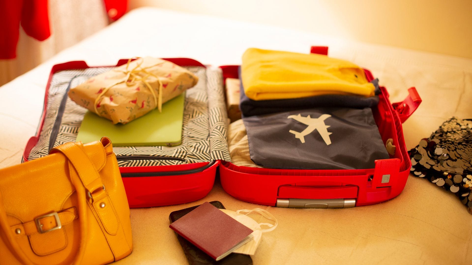Maleta de cabina abierta sobre una cama con todo el equipaje preparada para volar