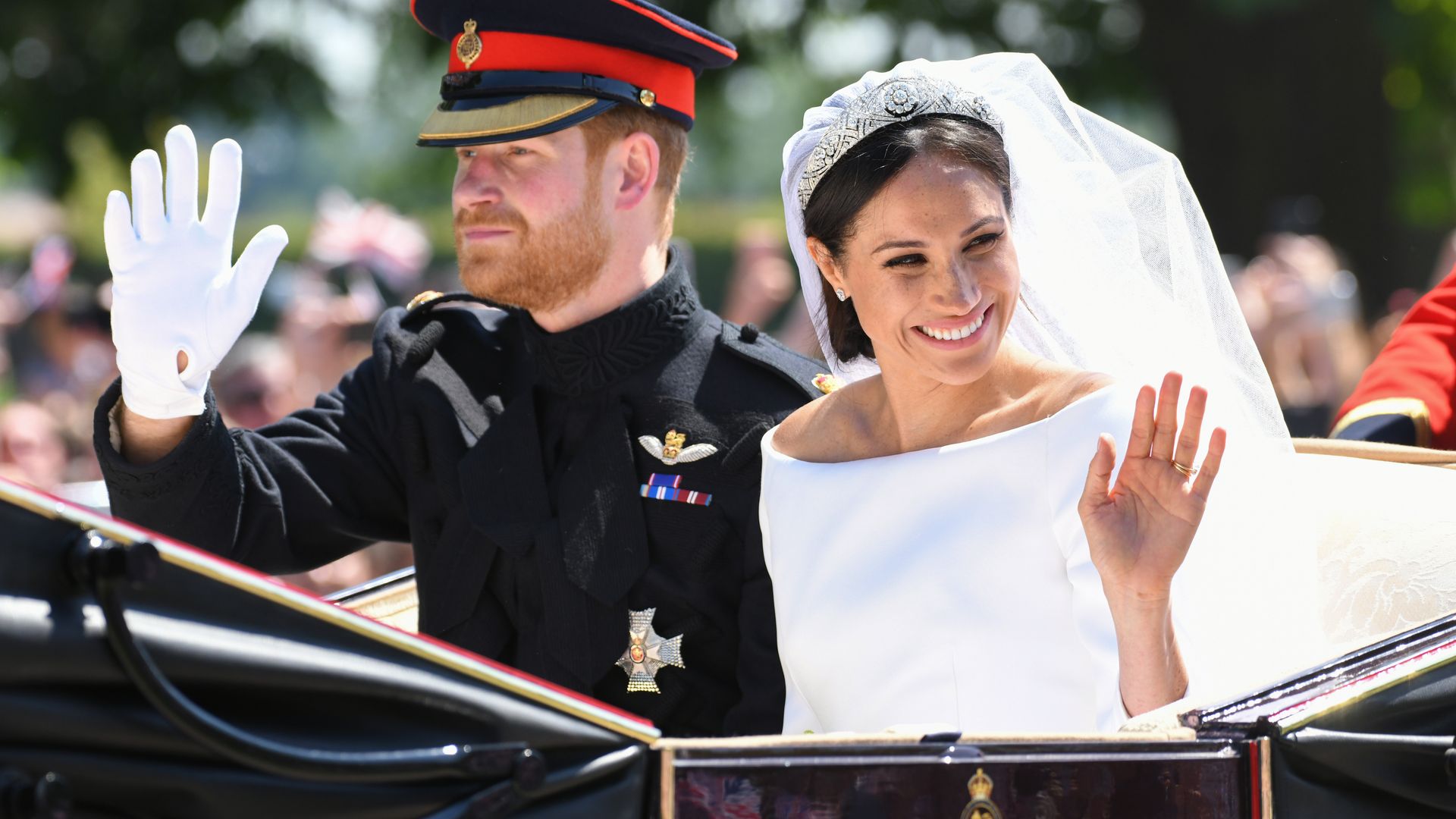 Plano medio de Harry y Meghan de Inglaterra saludando desde su carruaje tras la boda