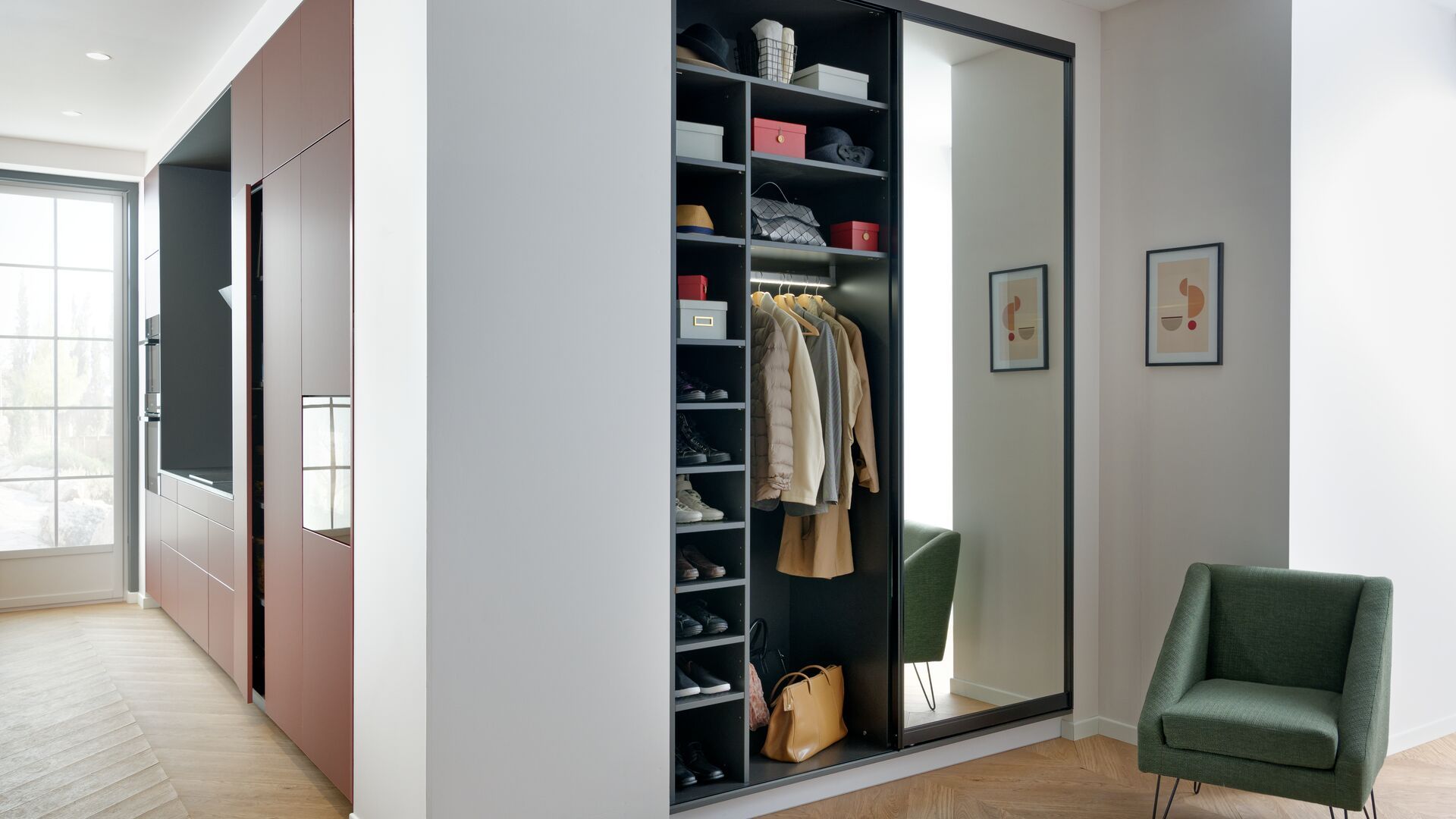 Recibidor abierto a la cocina con armario con puertas de espejo, zapatero interior, baldas y barra iluminada, butaca verde