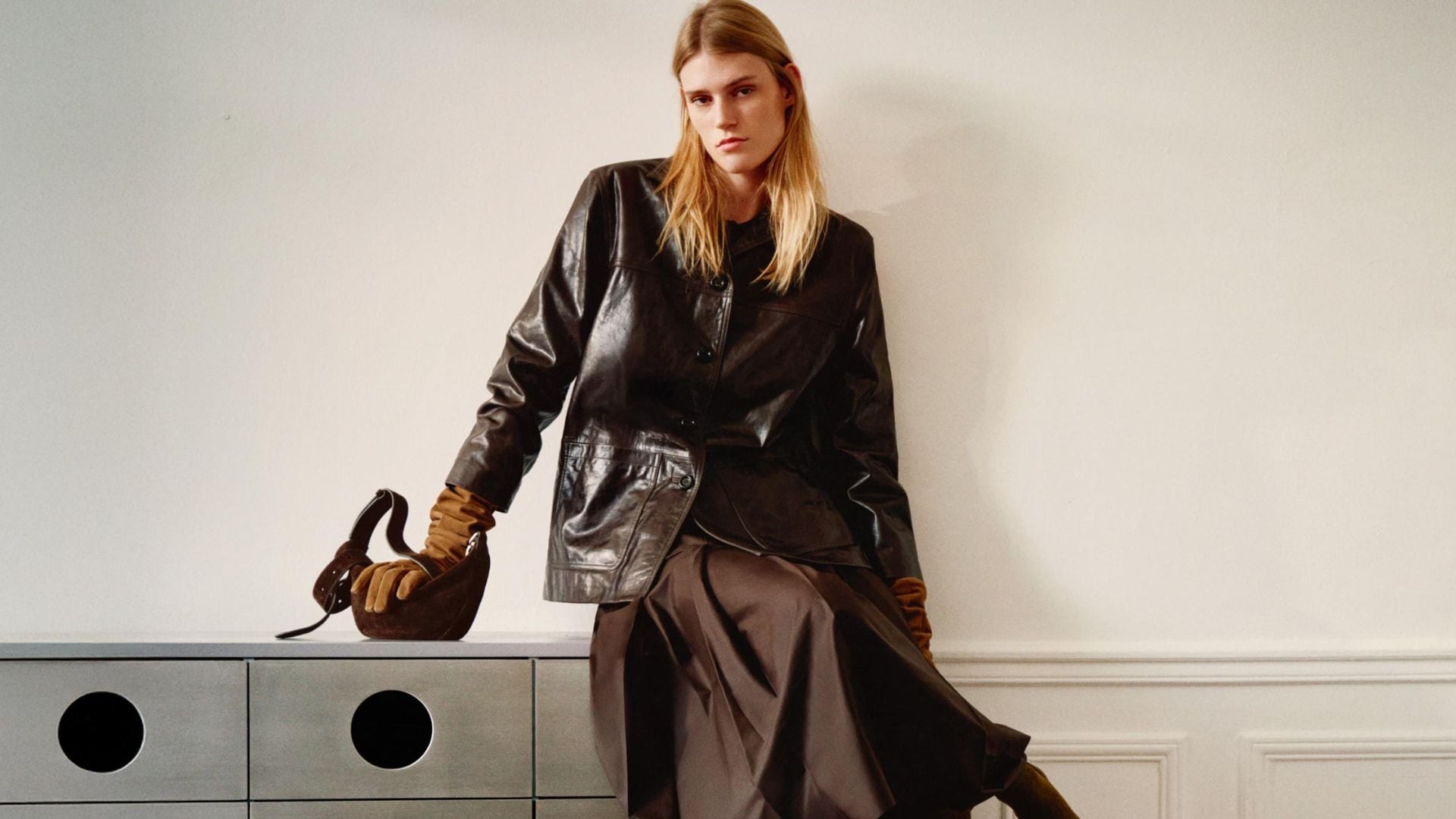 Modelo sentada en una cómoda con ropa de Massimo Dutti