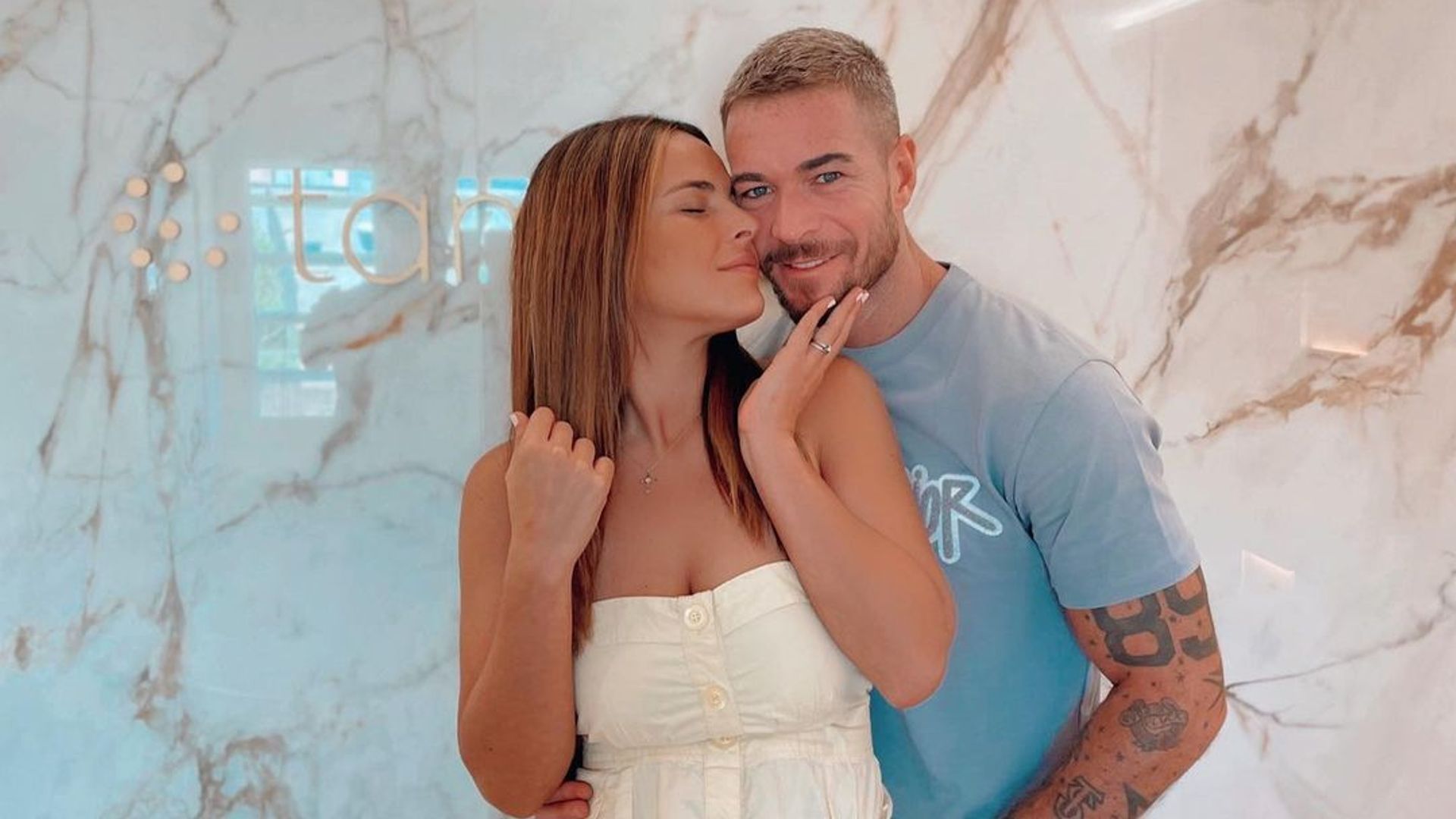 Plano medio de Marta Peñate y Tony Spina abrazados con look casual