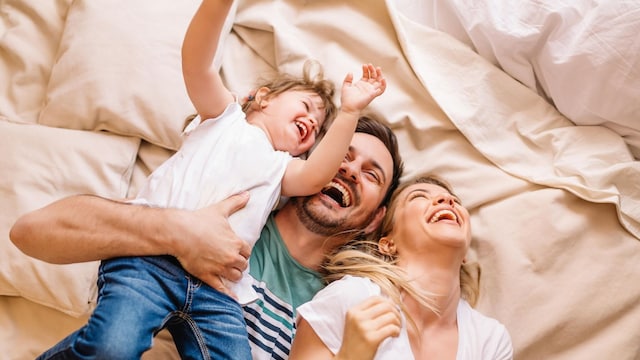 familia feliz jugando sobre una cama