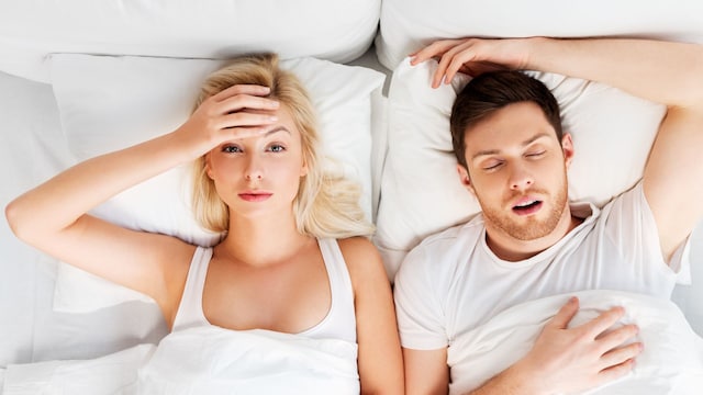 mujer sin poder dormir en la cama mientras su pareja ronca