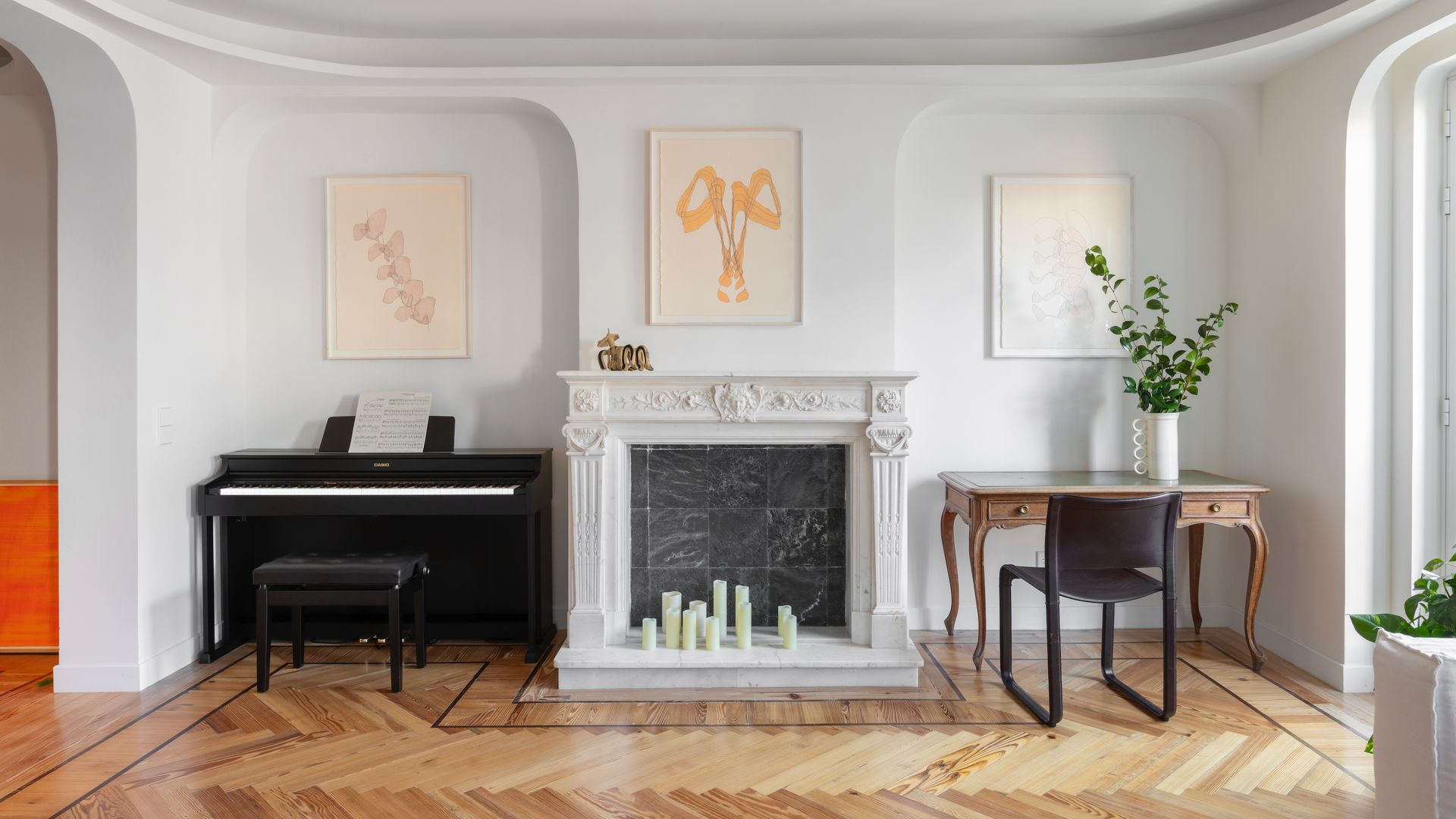 Salón con chimenea, piano y consola, suelo de madera, molduras y cuadros