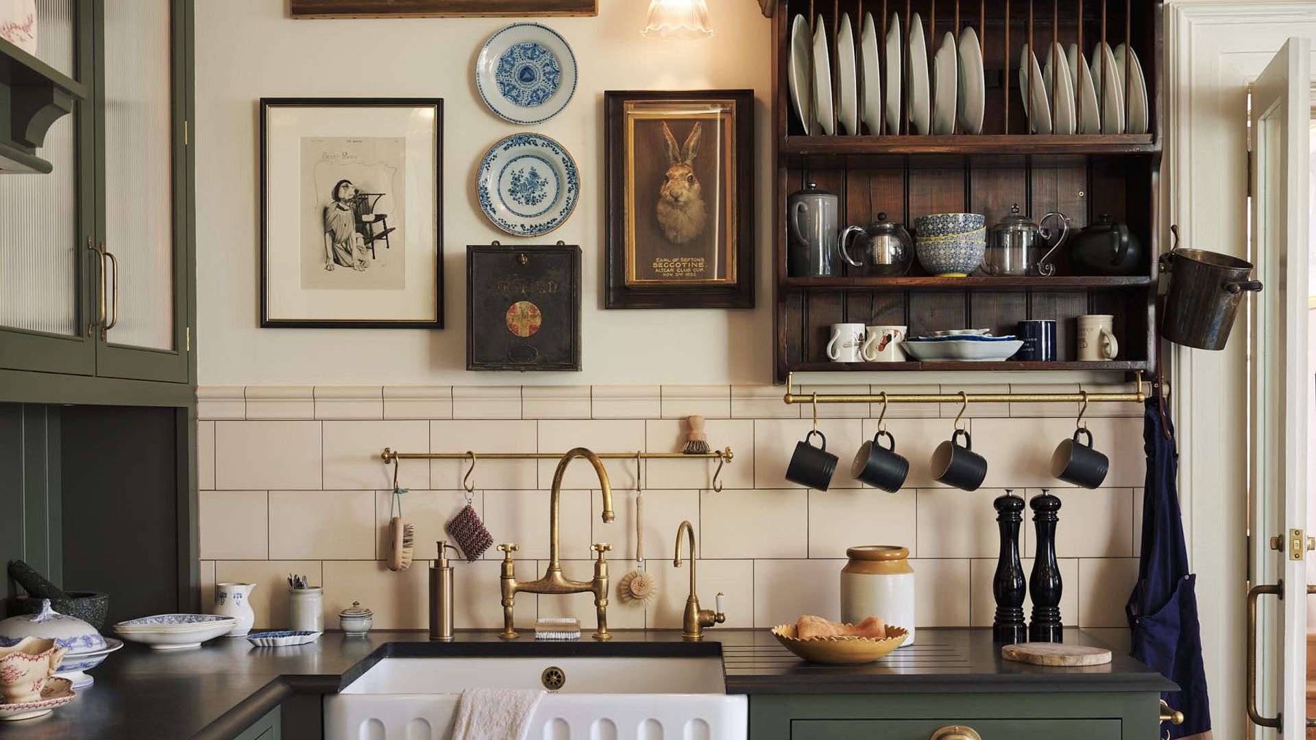 Cocina cottagecore con platero de madera, platos en la pared, cuadros y soporte para tazas 