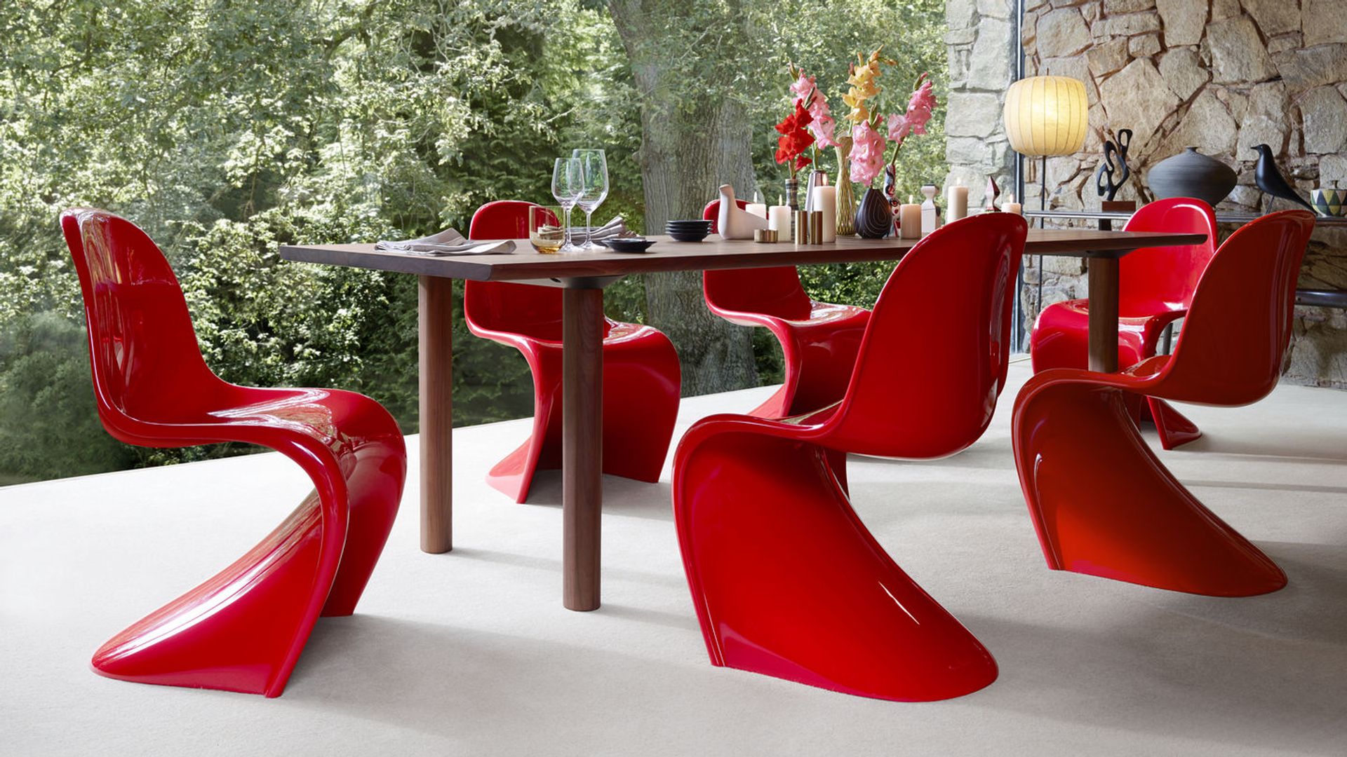 Comedor con gran ventanal, mesa Xl y sillas Panton en rojo brillante, jarrón con flores