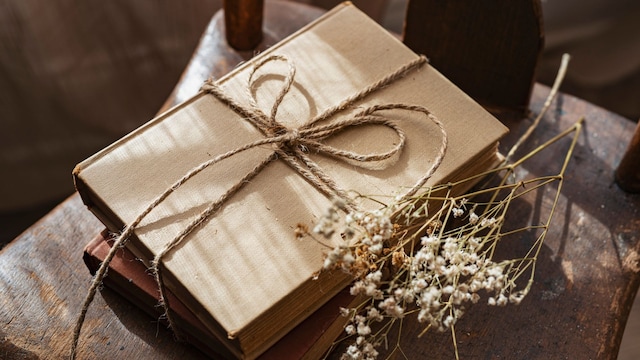 Libro envuelto para regalo con un lazo y unas pequeñas flores de paniculata sobre una silla de madera